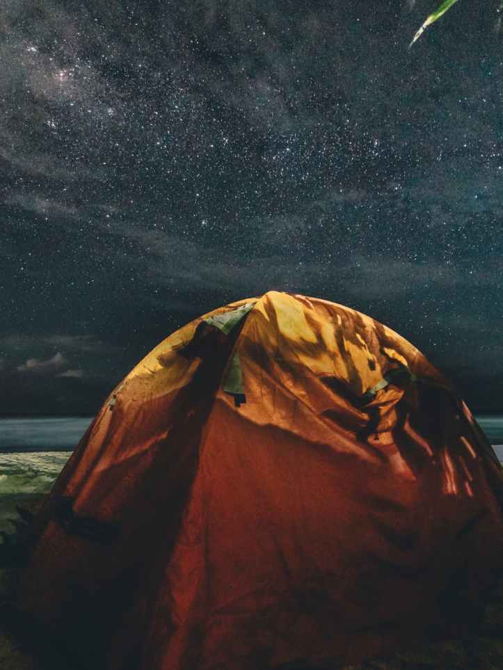 orange and green camping tent under starry sky